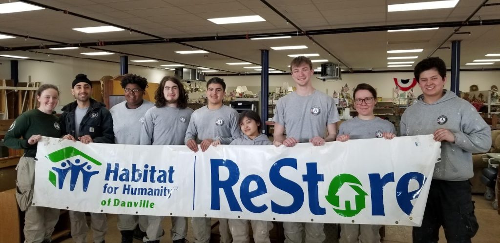 ReStore volunteers holding banner inside new facility.